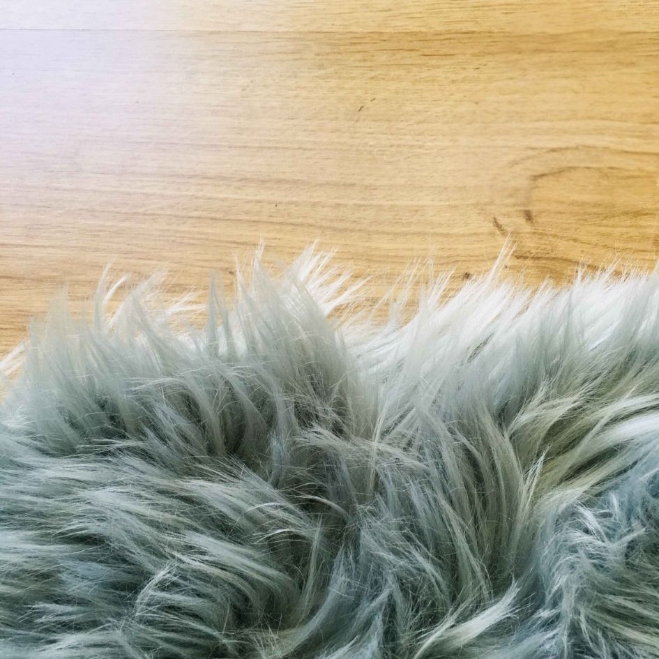 Pele artificial cinzenta peluda sobre madeira clara