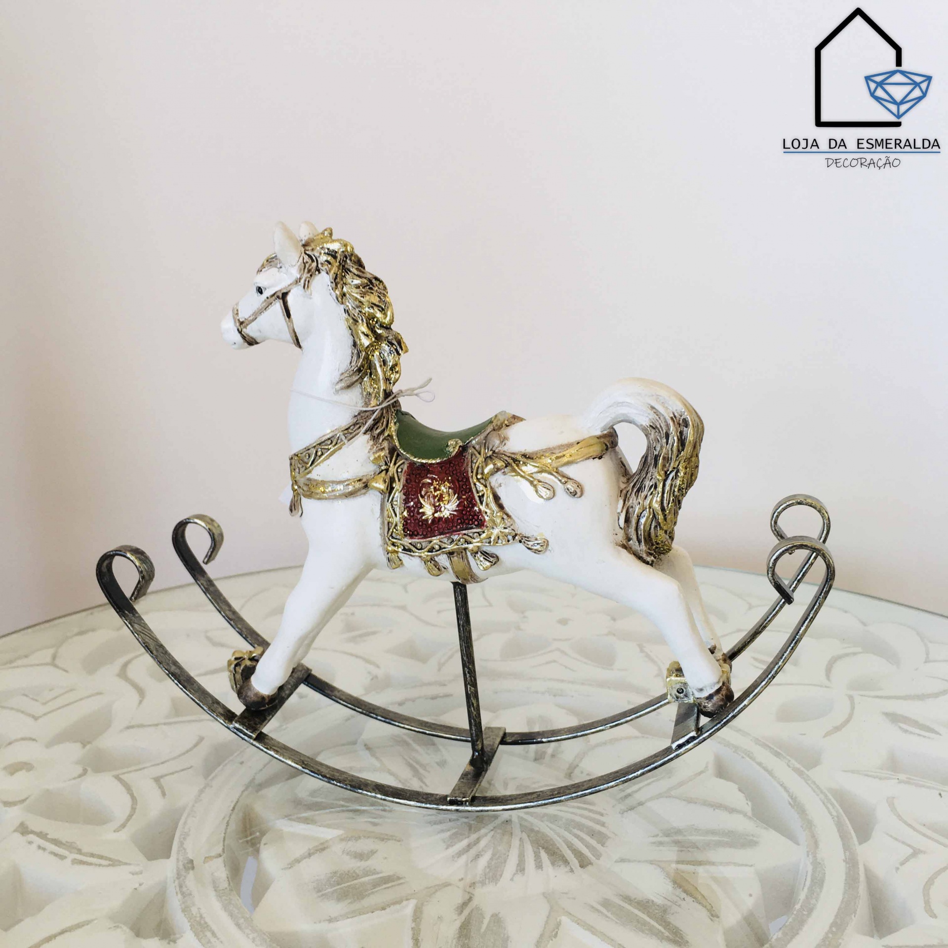 Cavalo de balanço decorativo branco com detalhes dourados e sela verde e vermelha