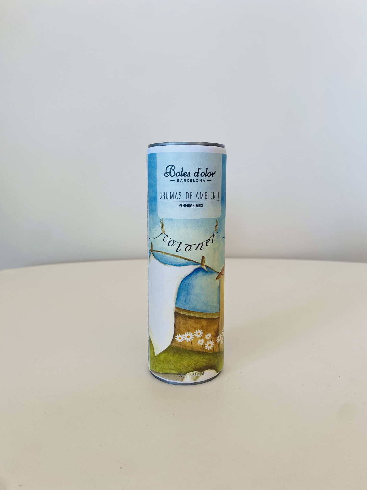 frasco cilíndrico de brumas de ambiente com etiqueta azul e verde