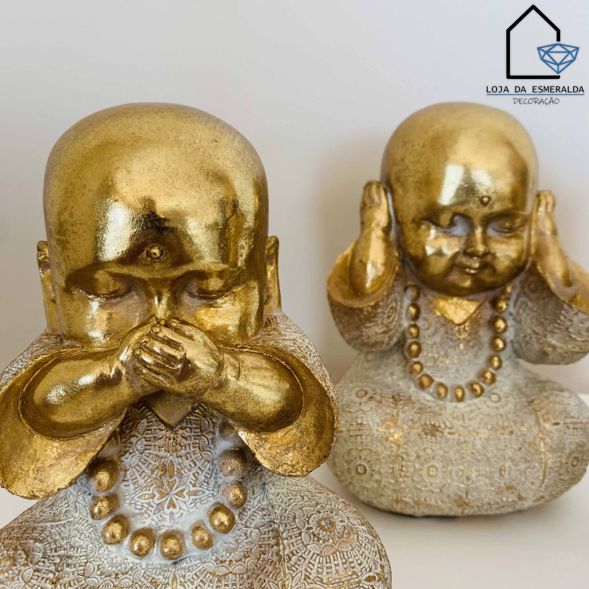 Duas estatuetas douradas e cinzentas de figuras infantis meditando