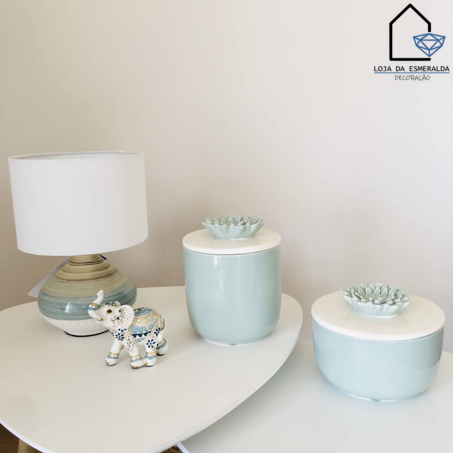 Decoração com potes de cerâmica, elefante decorativo e candeeiro sobre mesa branca