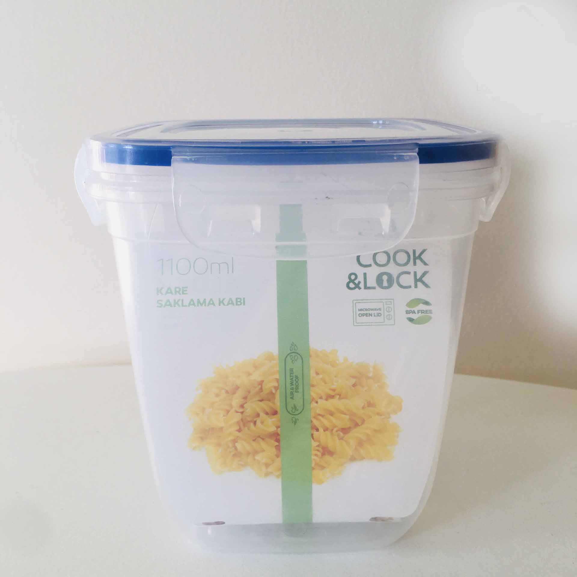 Recipiente plástico transparente com tampa azul e etiqueta com massa fusilli amarela