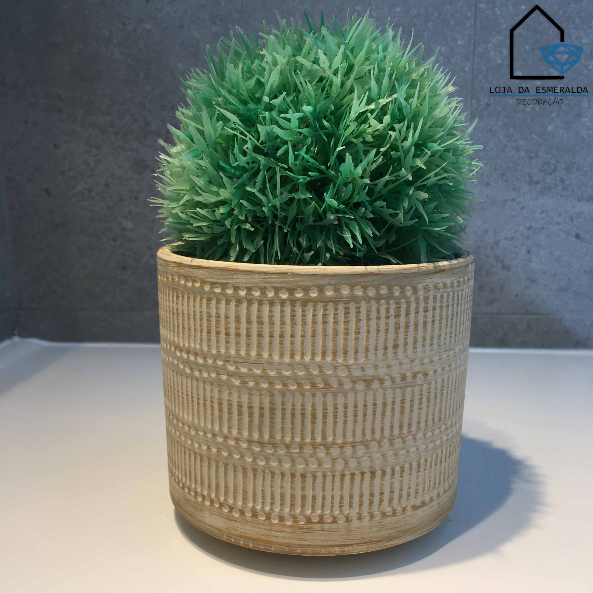 Vaso bege texturizado com planta artificial verde e logótipo Loja da Esmeralda no fundo