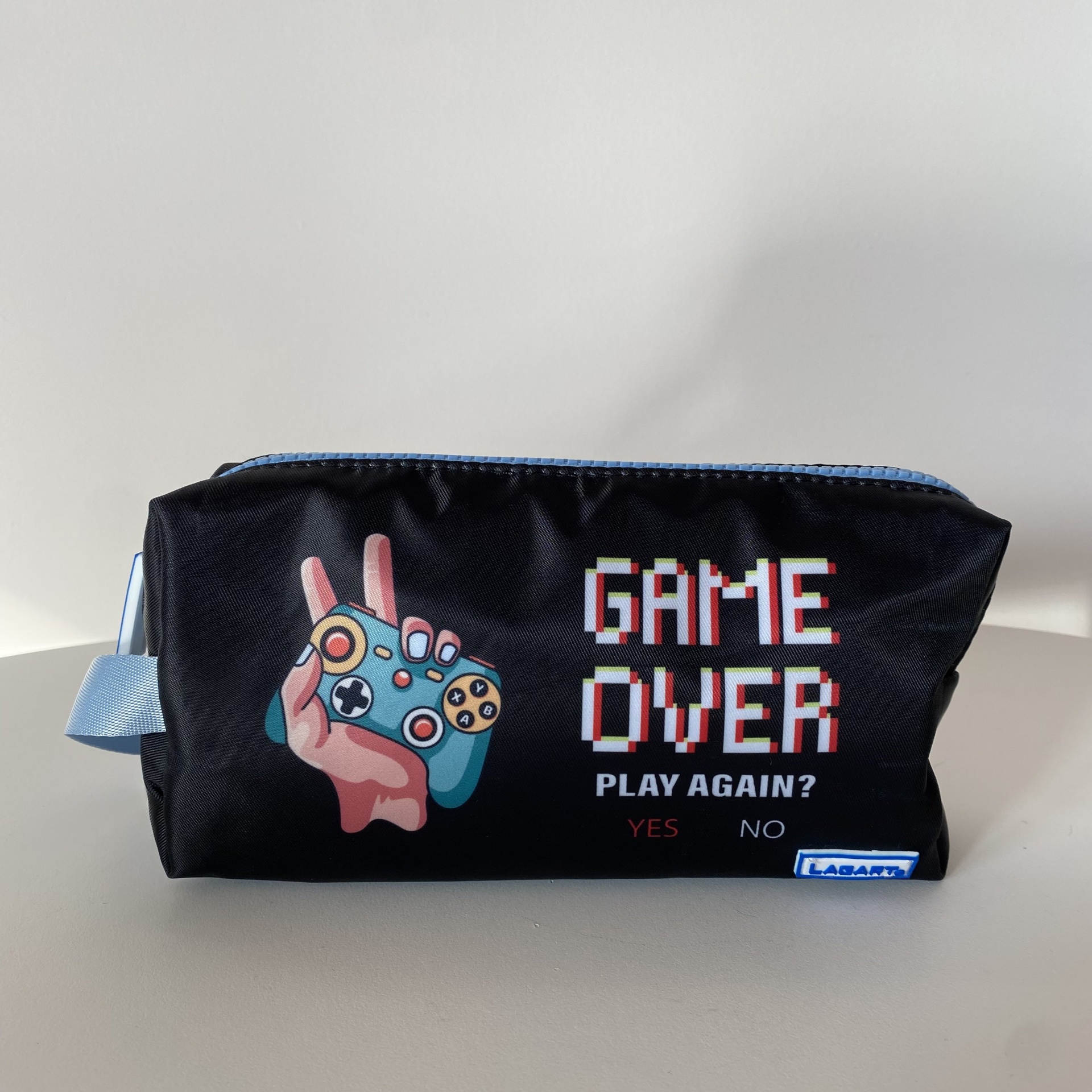 Estojo preto com fecho azul claro e texto 'GAME OVER PLAY AGAIN? YES NO' no lado