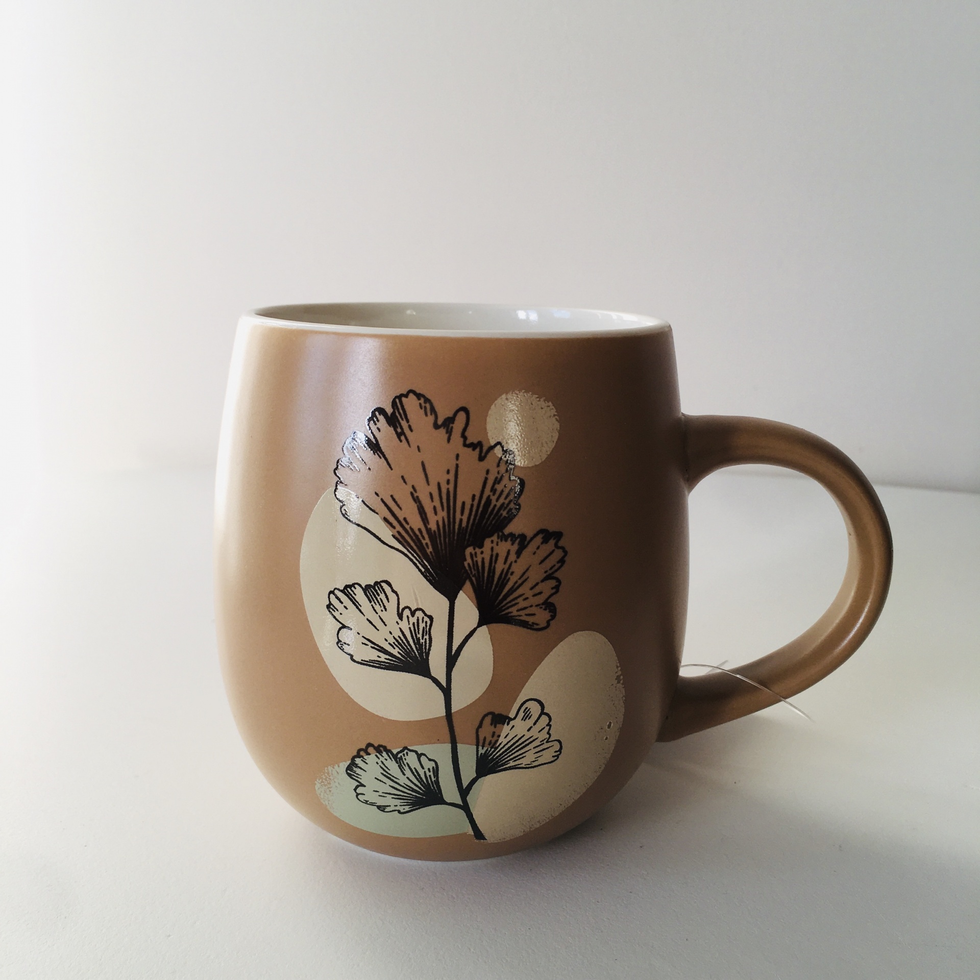 Caneca castanha com padrão de folhas e círculos pastel