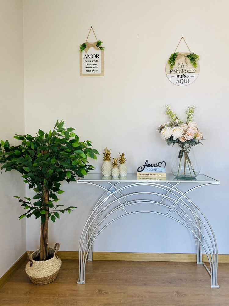 Decoração com mesa de vidro, flores, plantas e placas decorativas penduradas na parede