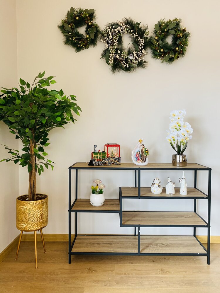 Estante metálica com prateleiras de madeira e decoração, planta alta em vaso dourado ao lado