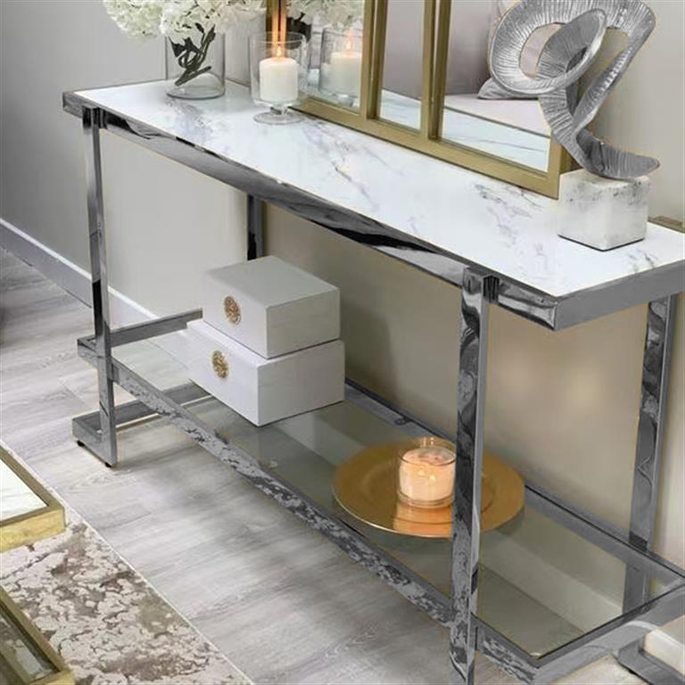 Consola moderna com tampo efeito mármore e estrutura metálica prateada polida, decorada com caixas brancas, vela e objetos decorativos.