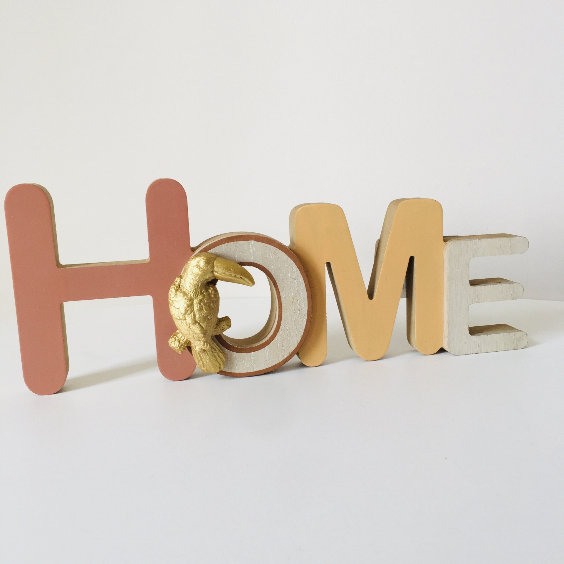 Decoração de letras tridimensionais a dizer HOME com pássaro dourado
