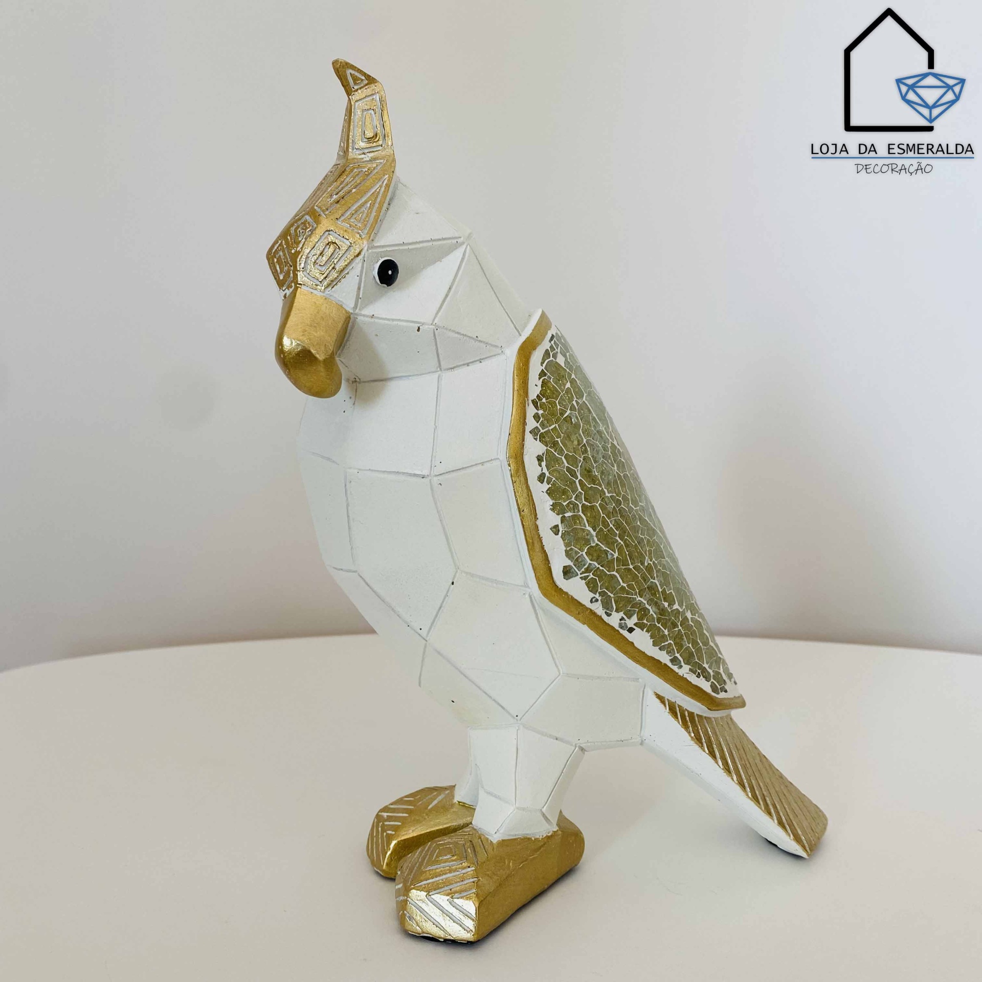 Estatueta geométrica de papagaio branco e dourado com textura na asa sobre superfície branca