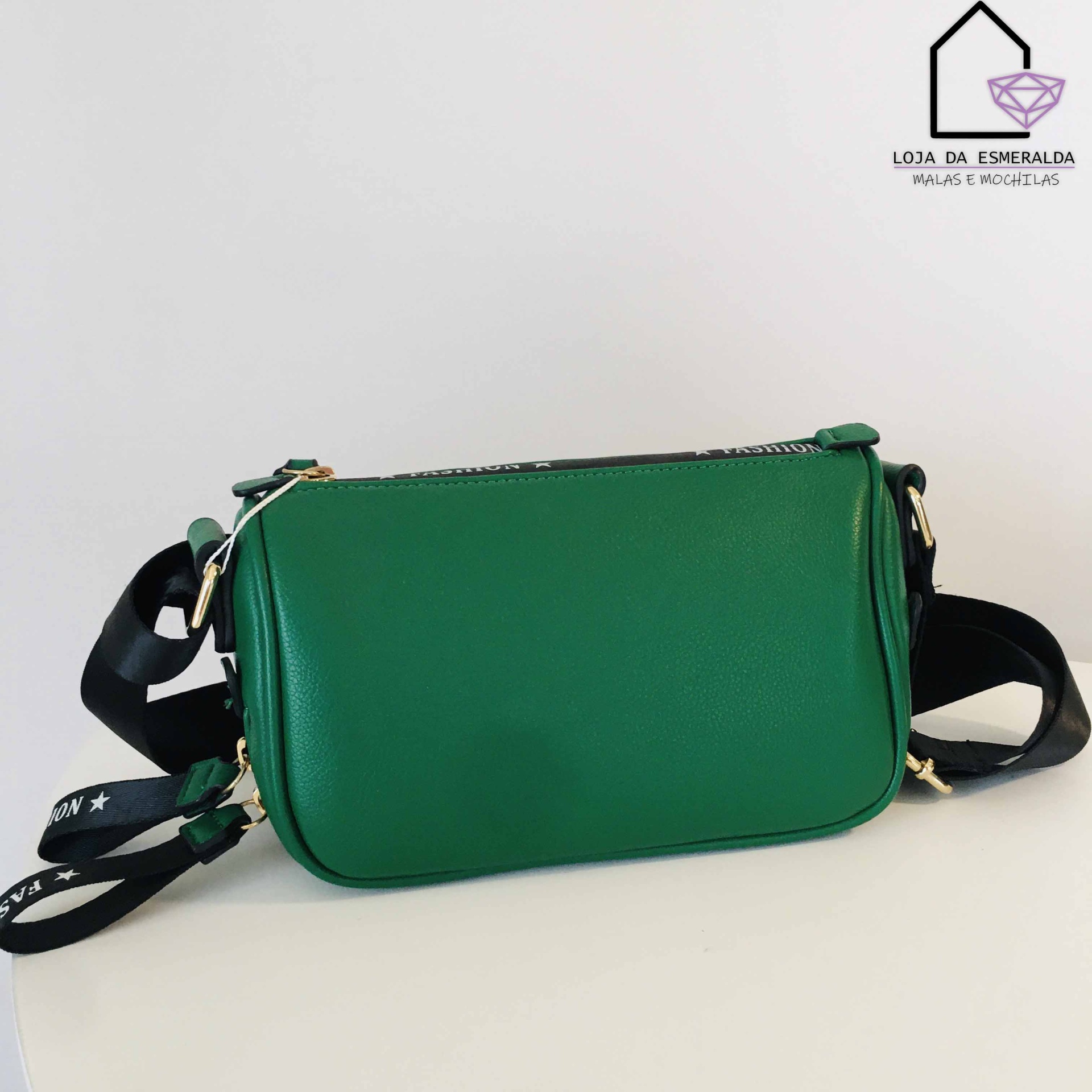 Bolsa verde com alça preta larga e logótipo de loja ao fundo