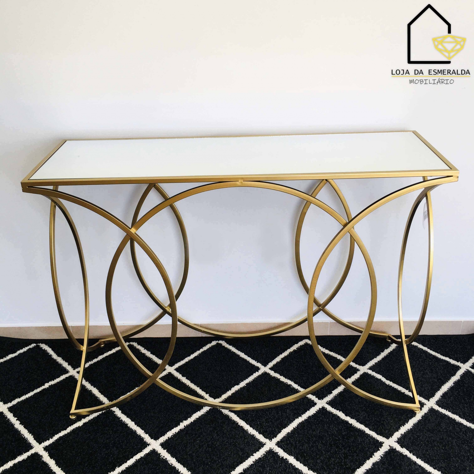 Consola de hall dourada com tampo branco e tapete preto com padrão branco