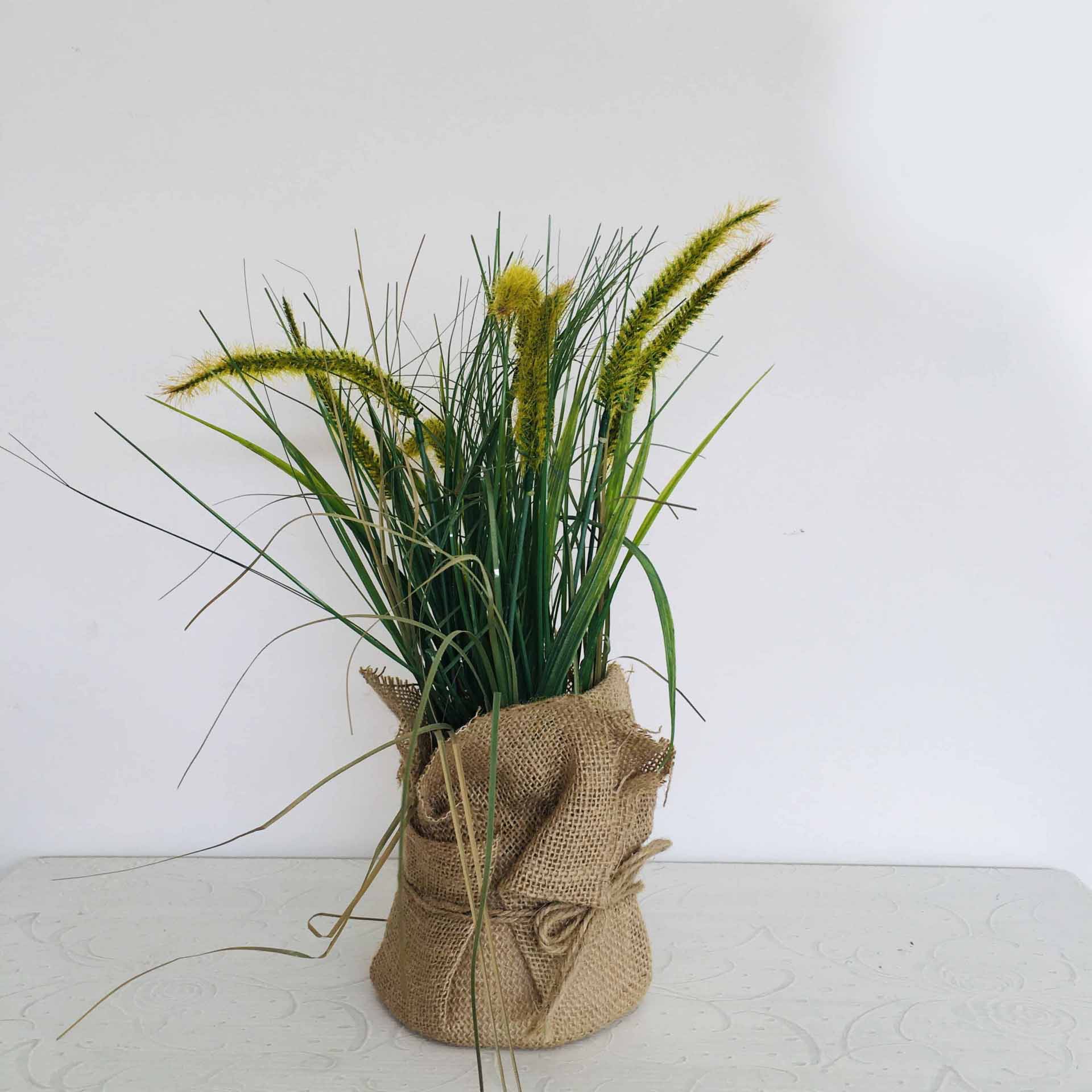 Arranjo de plantas artificiais com vaso em tecido rústico castanho