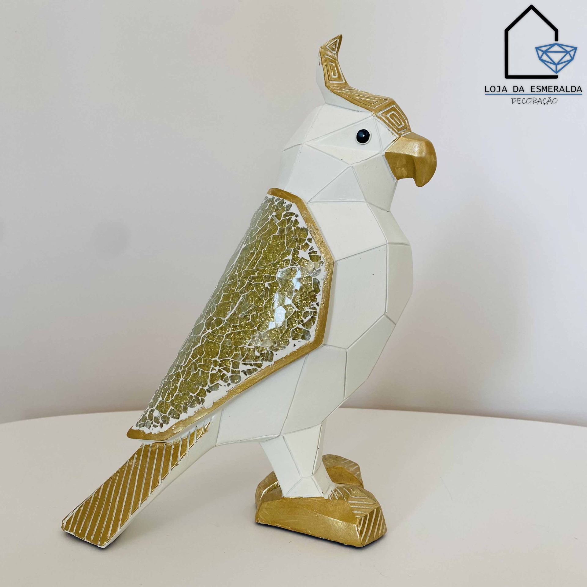 Estátua decorativa de cacatua branca com detalhes dourados e asa texturizada, sobre superfície branca