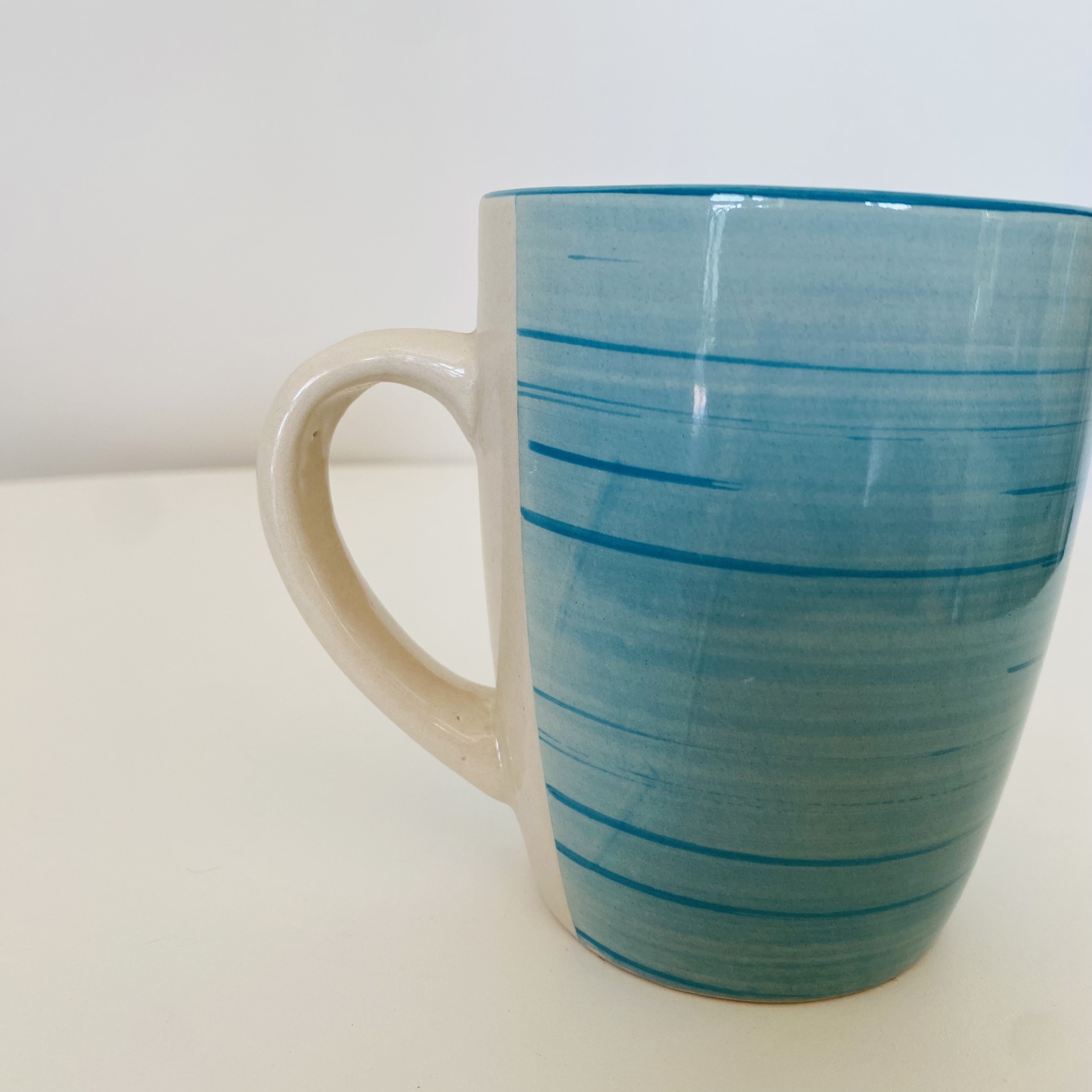 Caneca de cerâmica azul com linhas horizontais e pega branca