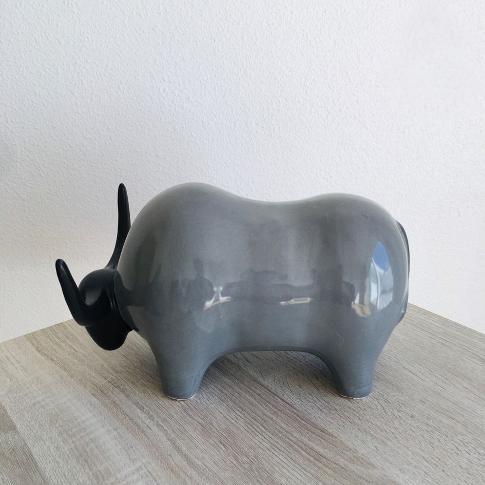Escultura de touro cinza com chifres pretos sobre mesa de madeira