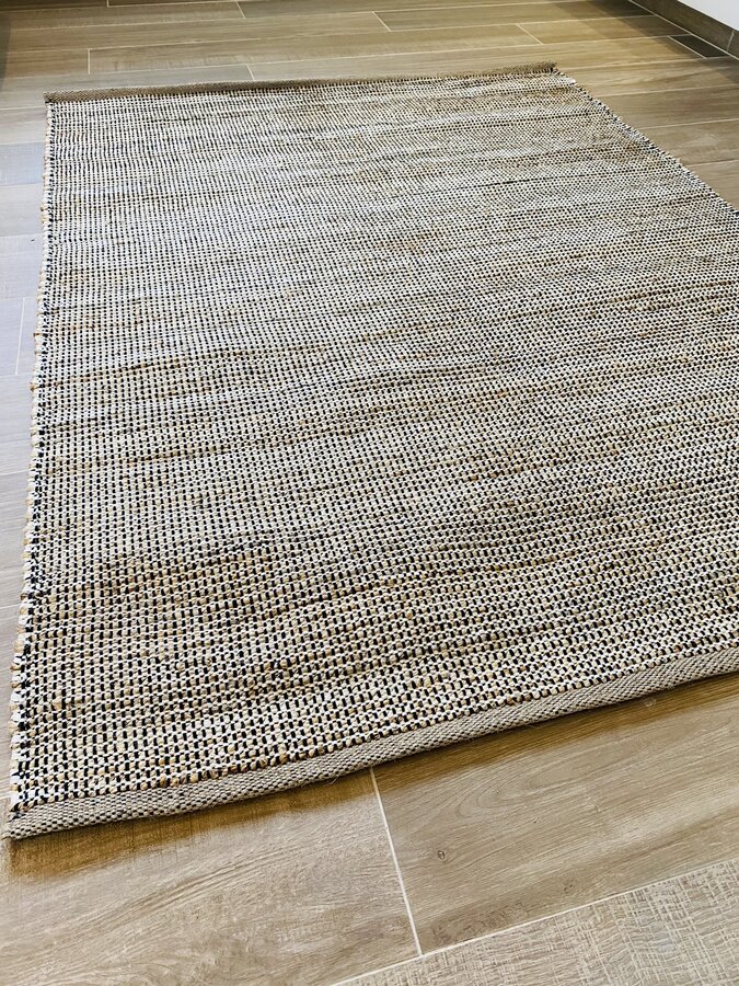 Tapete de padrões bege, castanho e preto sobre chão de azulejos castanhos