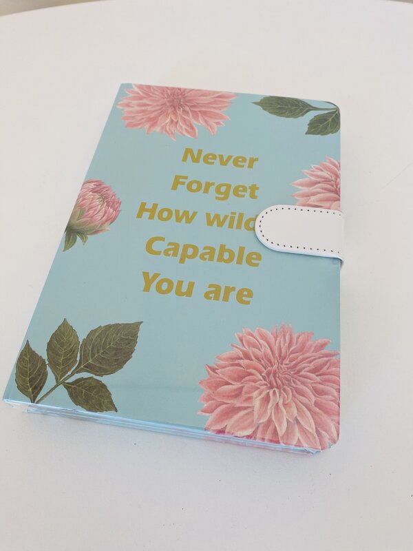 Capa de agenda azul com flores e texto inspirador em dourado