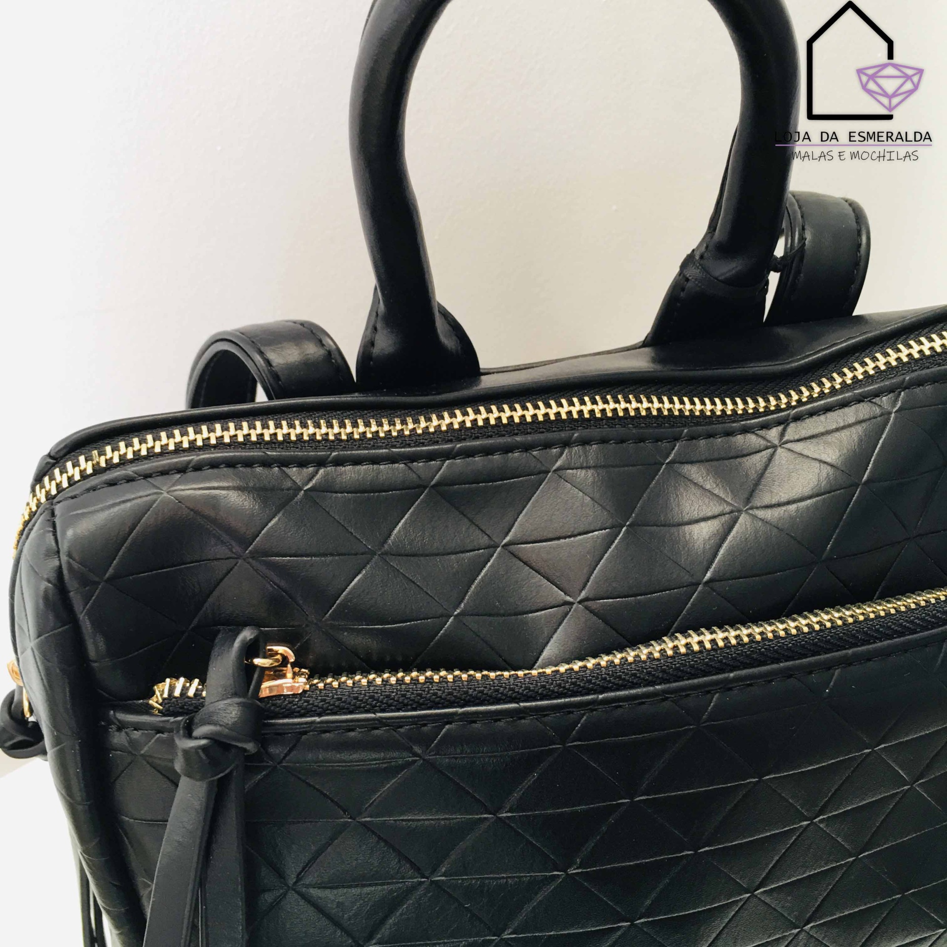 Mala preta com fechos dourados e textura acolchoada em padrão de losangos