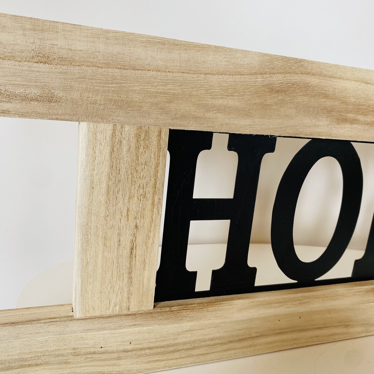 Placa decorativa de madeira clara com texto metálico preto e branco