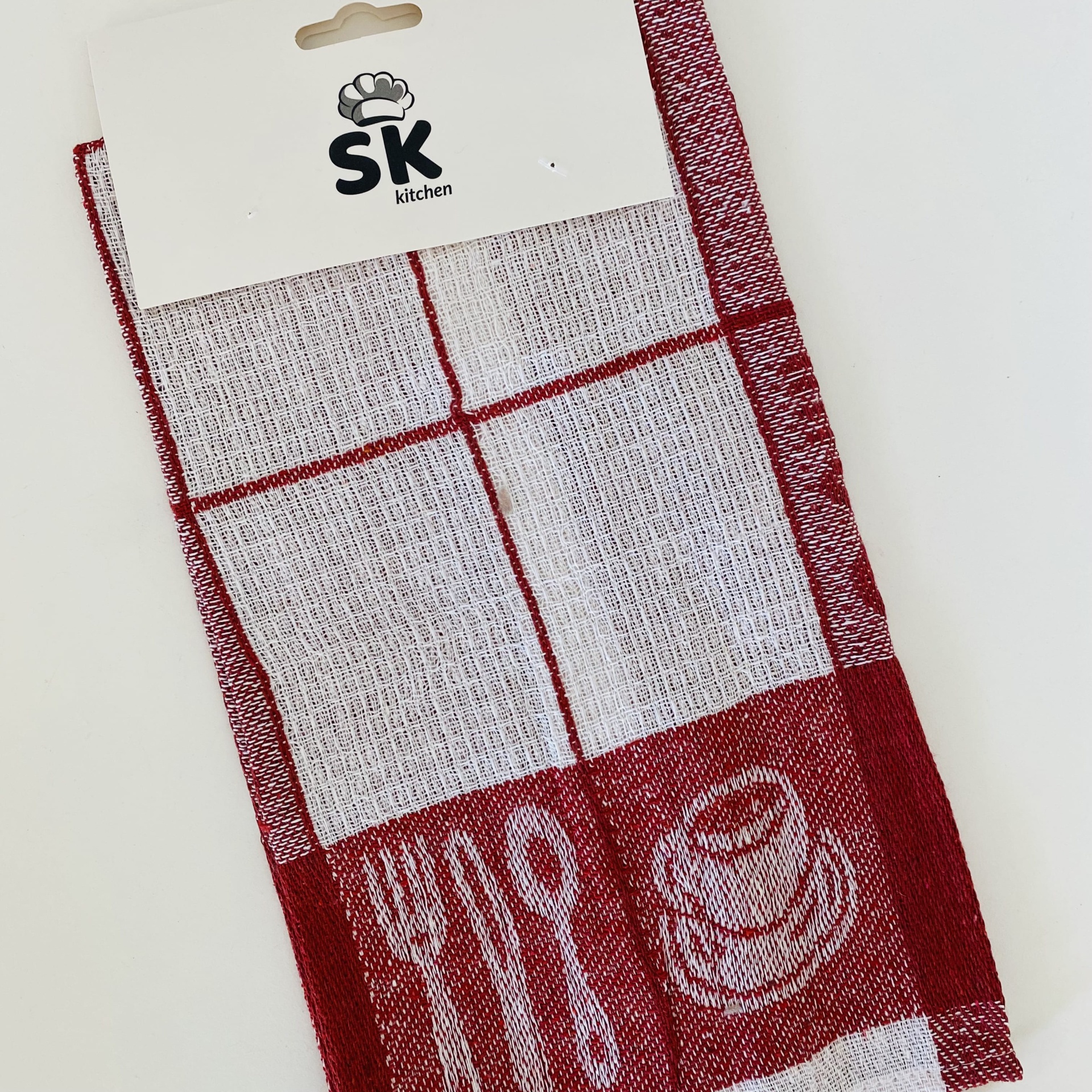 Pano de cozinha vermelho e branco com padrão de quadrados e ícones de talheres e chávena.