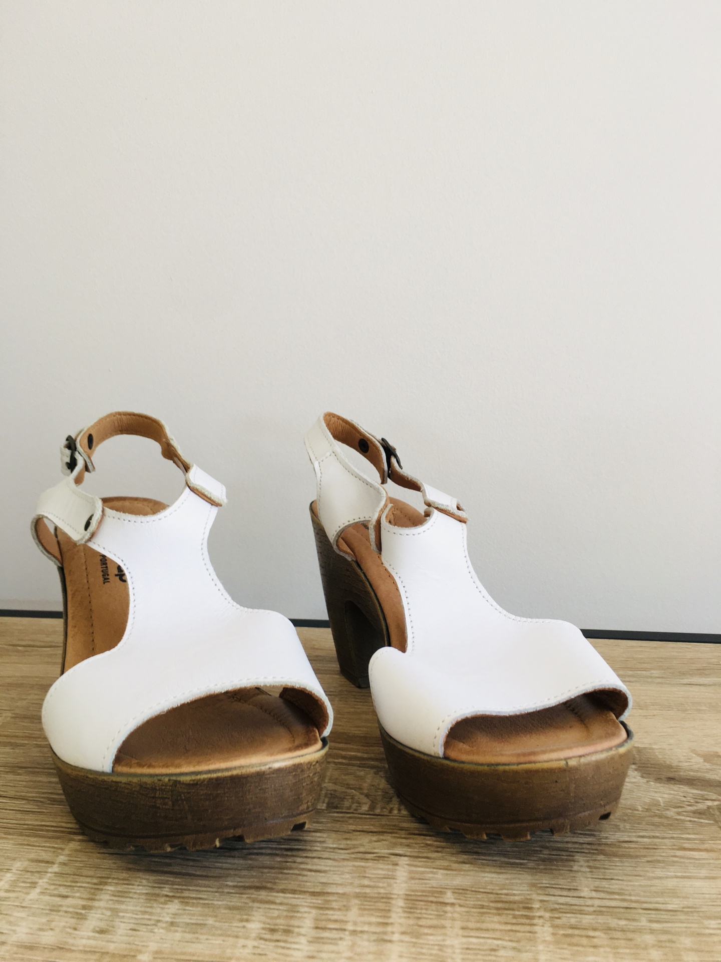 Sandálias de salto alto em couro branco com plataforma de madeira.