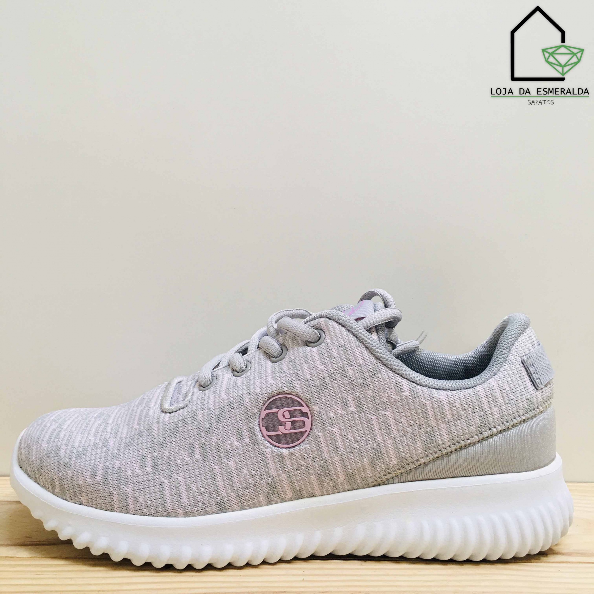 Tênis desportivo cinza claro com sola branca ondulada e logótipo SC rosa