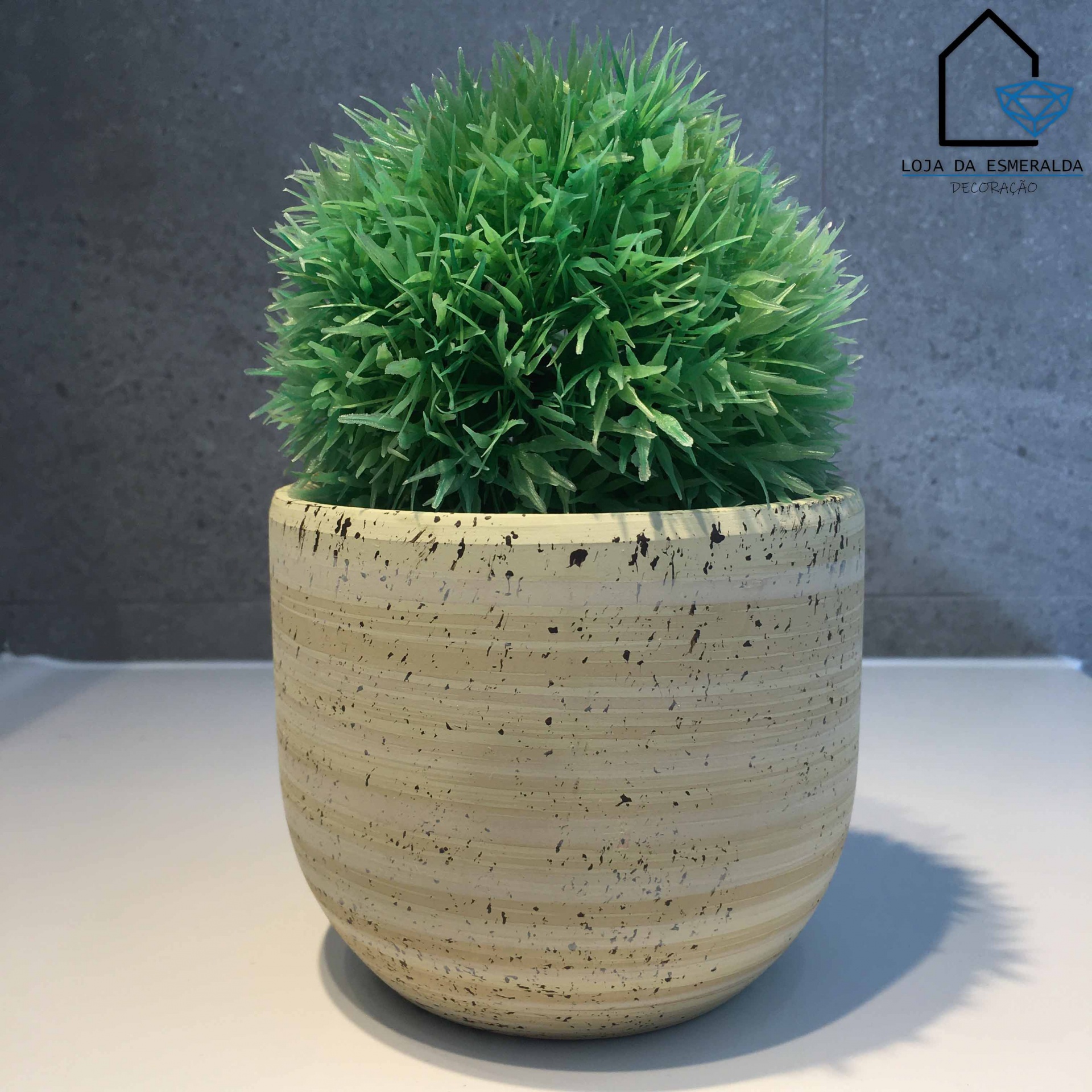 Vaso de cerâmica creme com planta artificial verde em fundo cinza