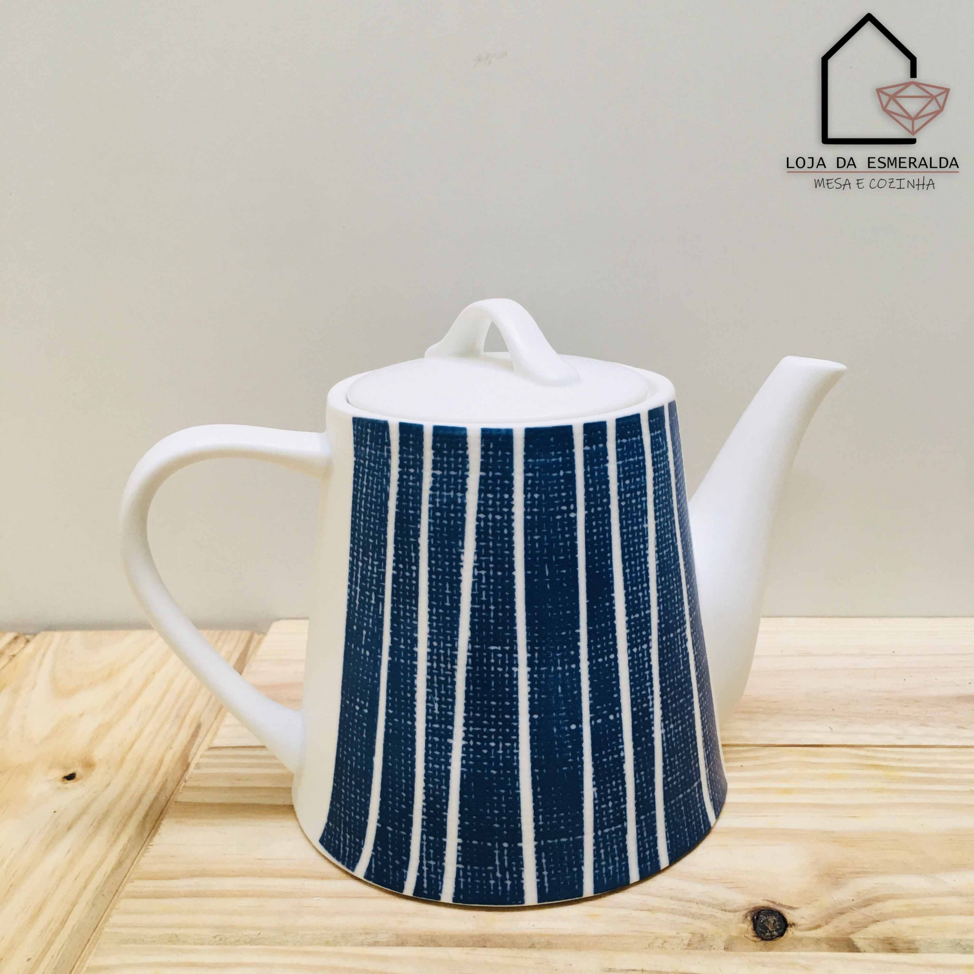 Bule de porcelana branca com riscas azuis e tampa, sobre mesa de madeira