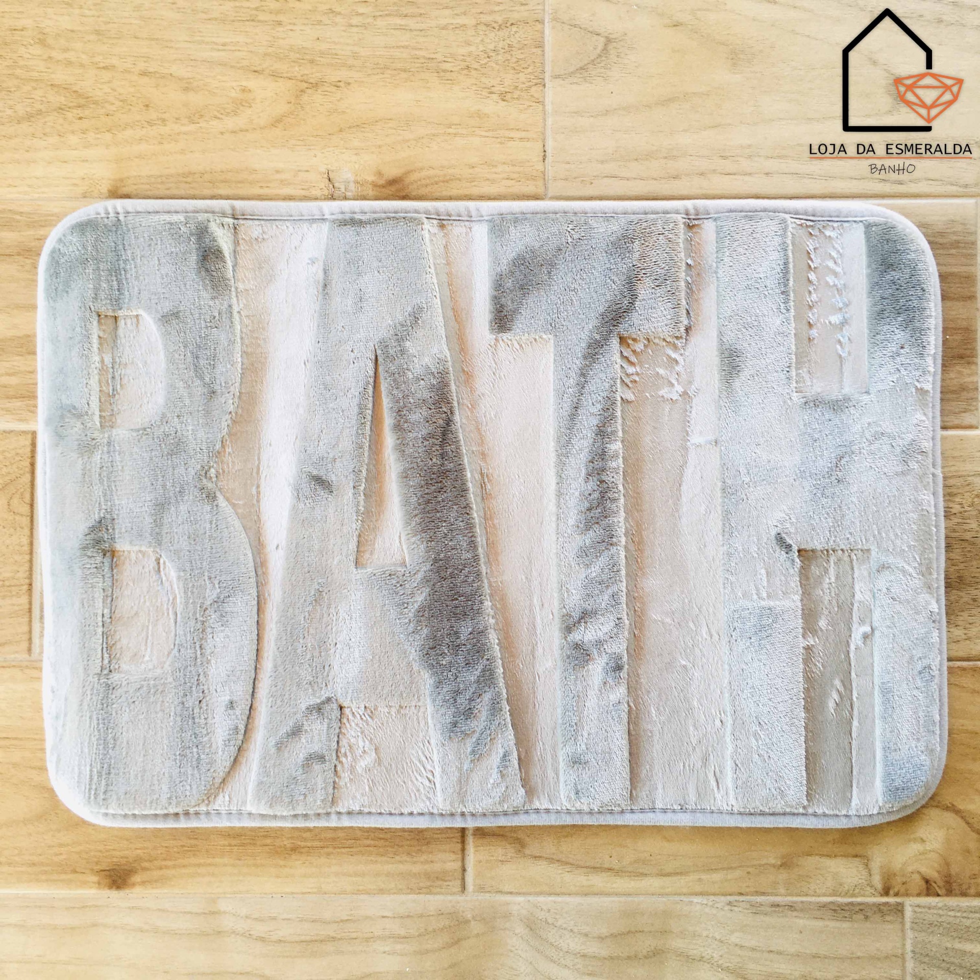 Tapete cinza e branco com a palavra BATH em relevo em piso de madeira clara