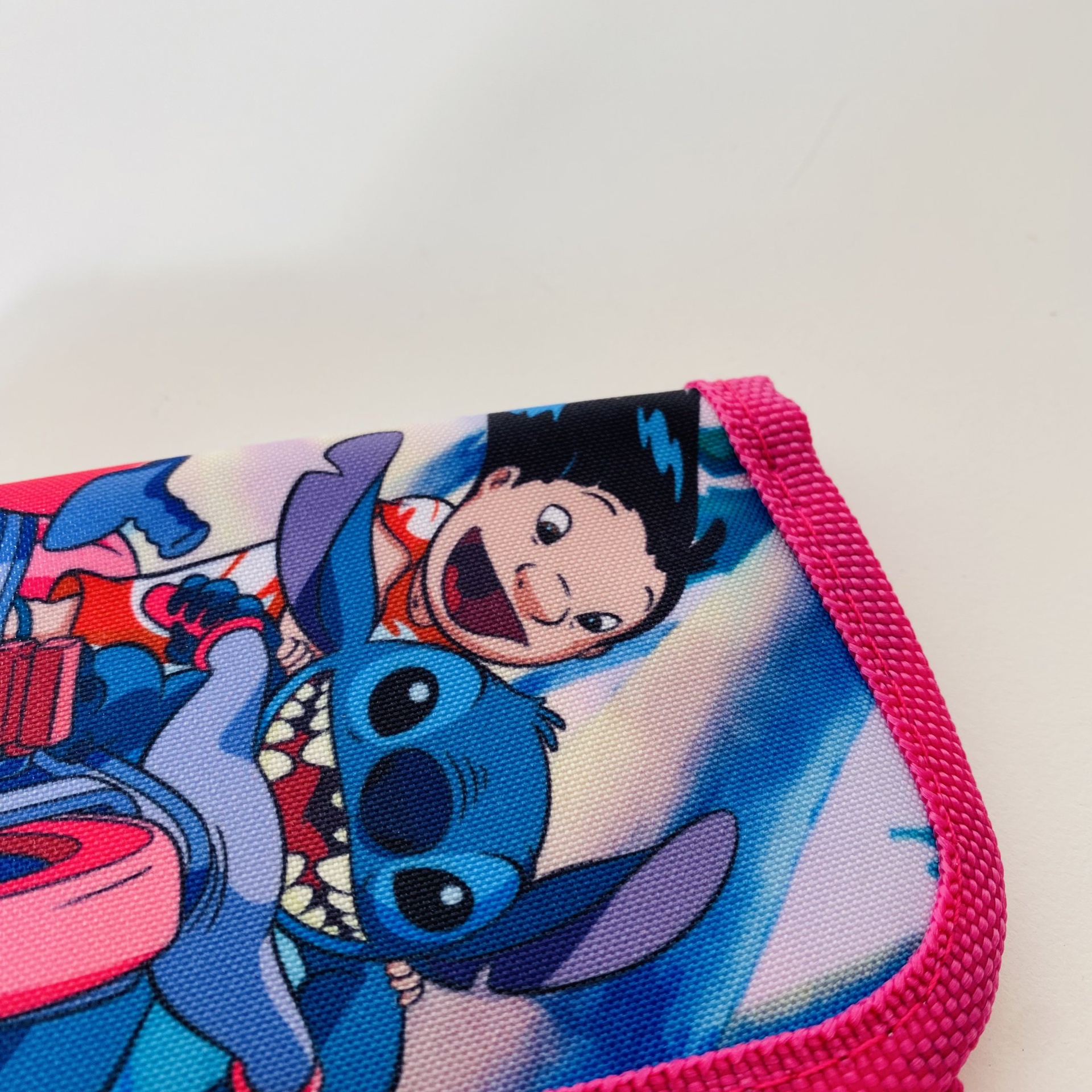 Tecido estampado com personagem Stitch e menino, borda rosa