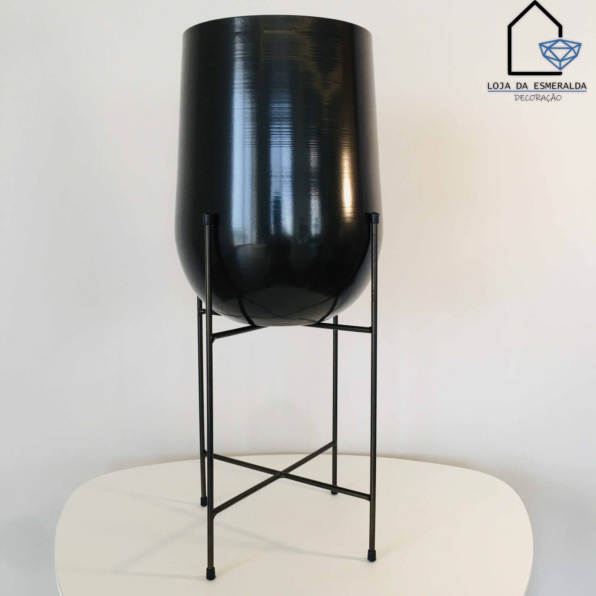 Vaso decorativo preto em suporte metálico sobre mesa branca