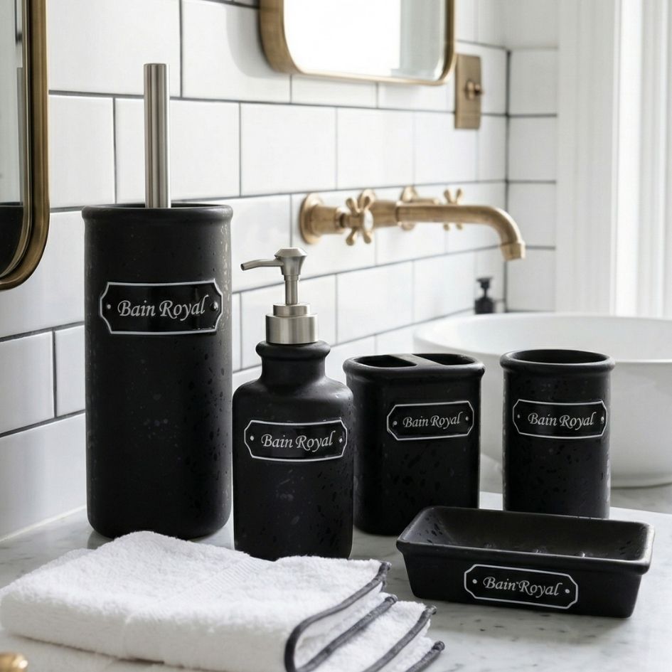 Acessórios de casa de banho em cerâmica preta com etiqueta Bain Royal num ambiente com bancada de mármore e azulejos brancos.