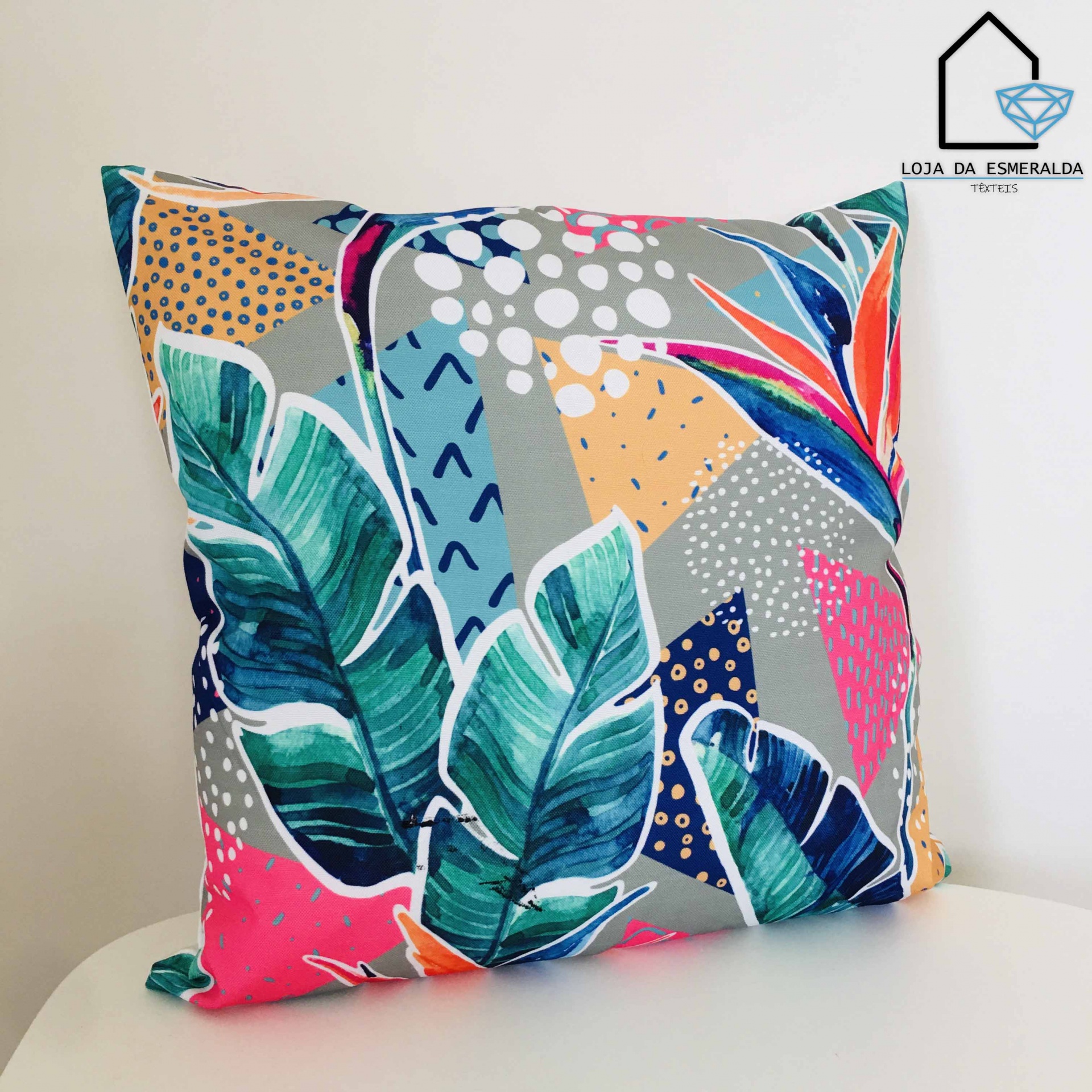 Almofada colorida com padrão de folhas e formas geométricas