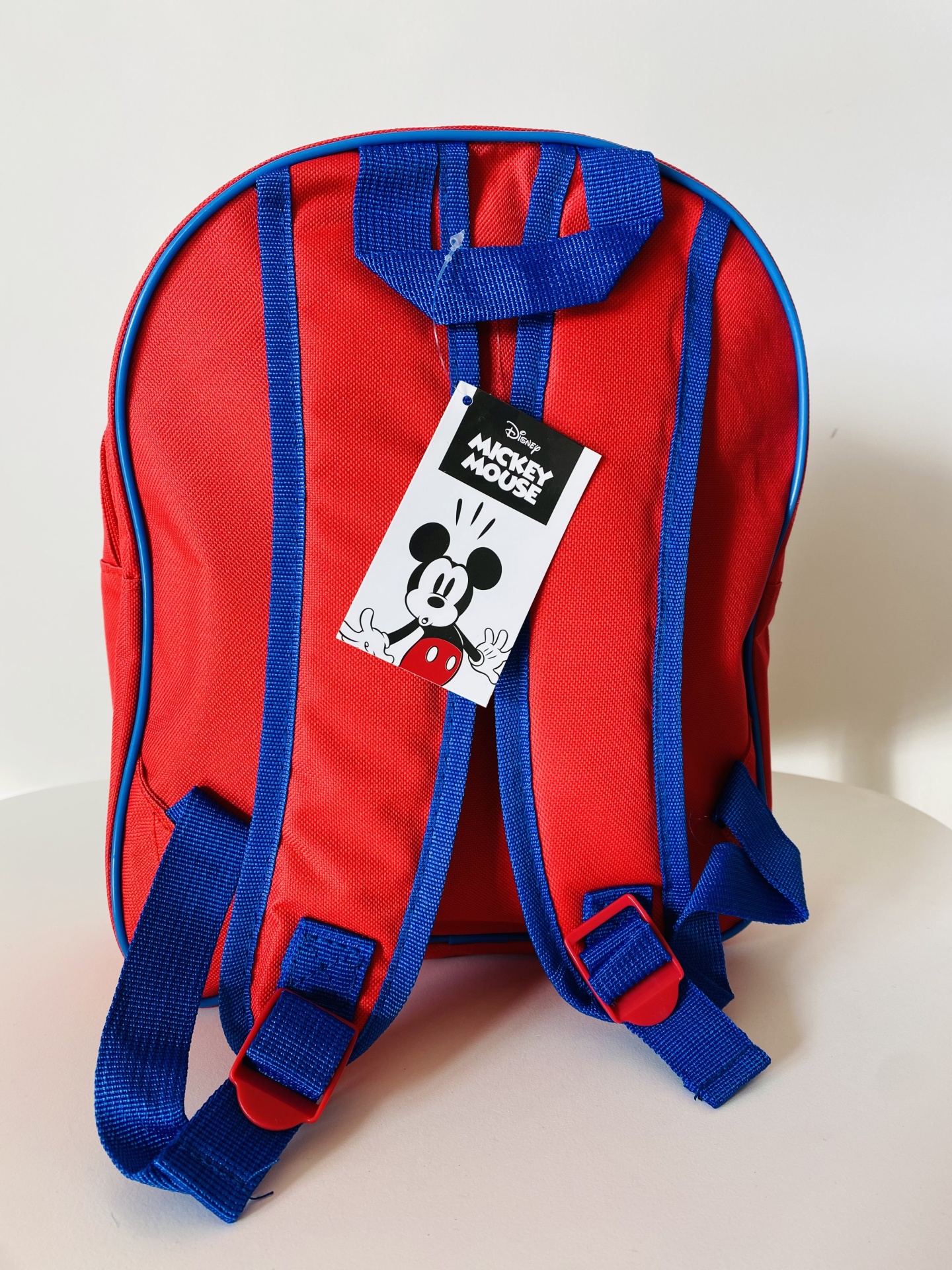 Mochila vermelha com alças azuis e etiqueta Disney Mickey Mouse