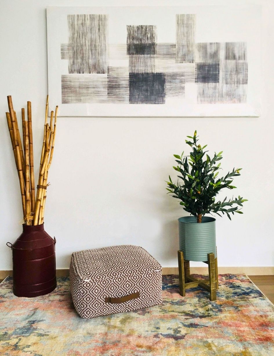 Vaso metálico com bambu, pufe geométrico, planta em vaso azul com suporte, quadro abstrato preto e branco