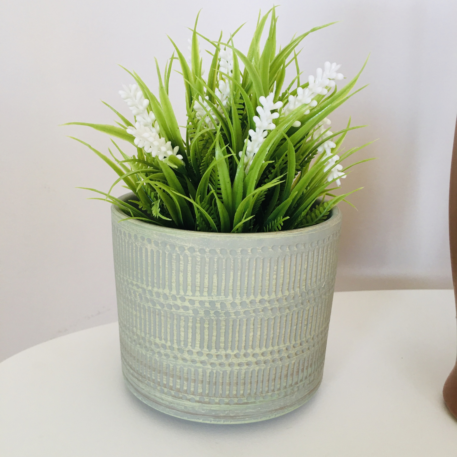 Vaso cinzento texturizado com planta artificial verde com flores brancas