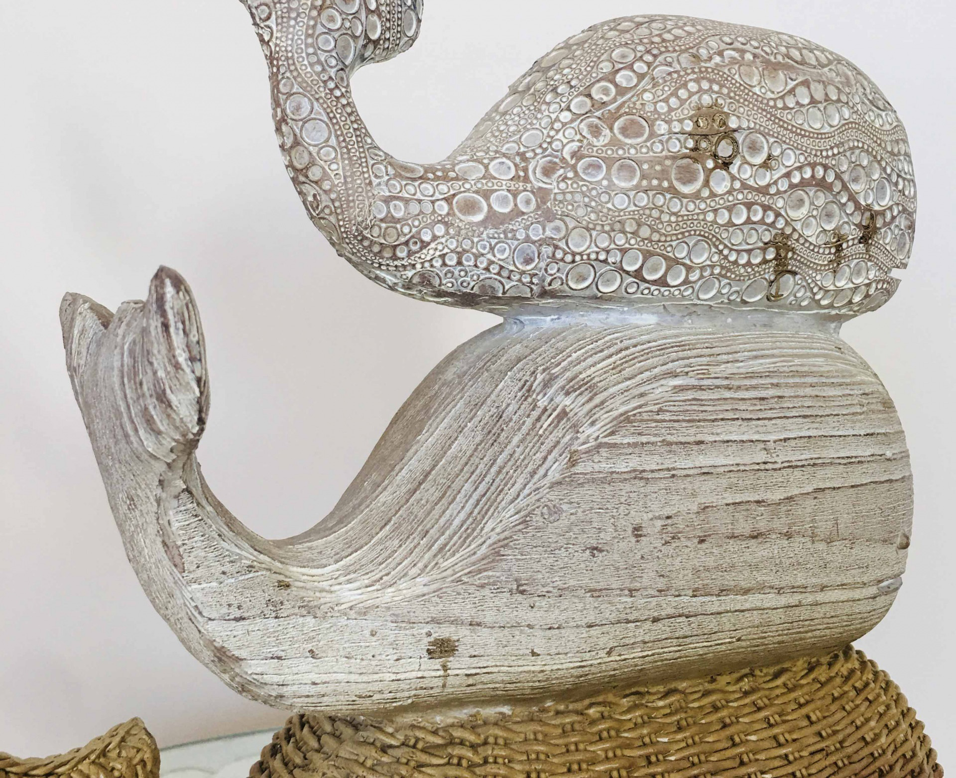 Escultura decorativa de baleia em madeira branca envelhecida sobre base em vime