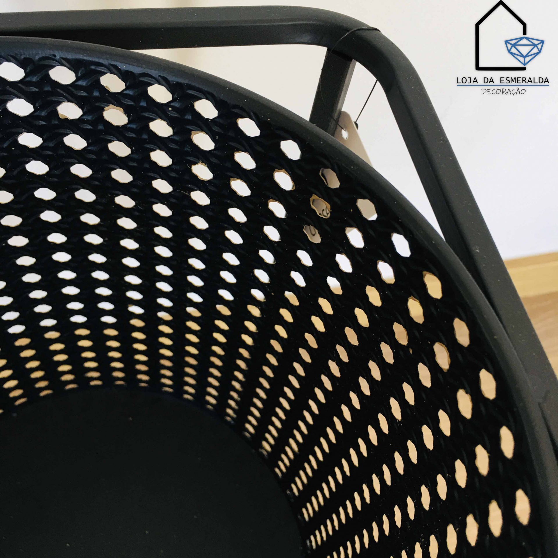 Cesto preto perfurado com estrutura metálica ao lado do logotipo LOJA DA ESMERALDA