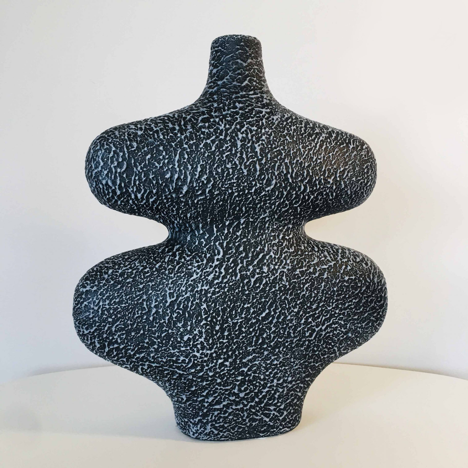 Vaso decorativo preto com padrão branco e formato curvo