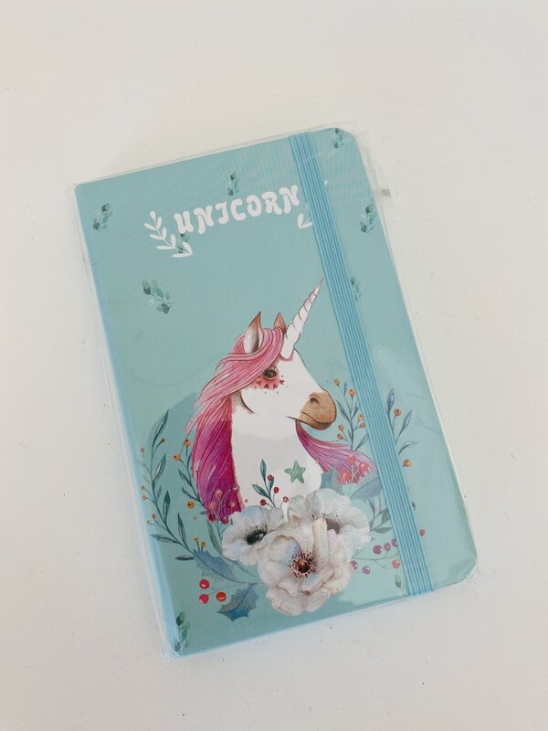 Caderno azul claro com desenho de unicórnio com crina rosa e flores brancas