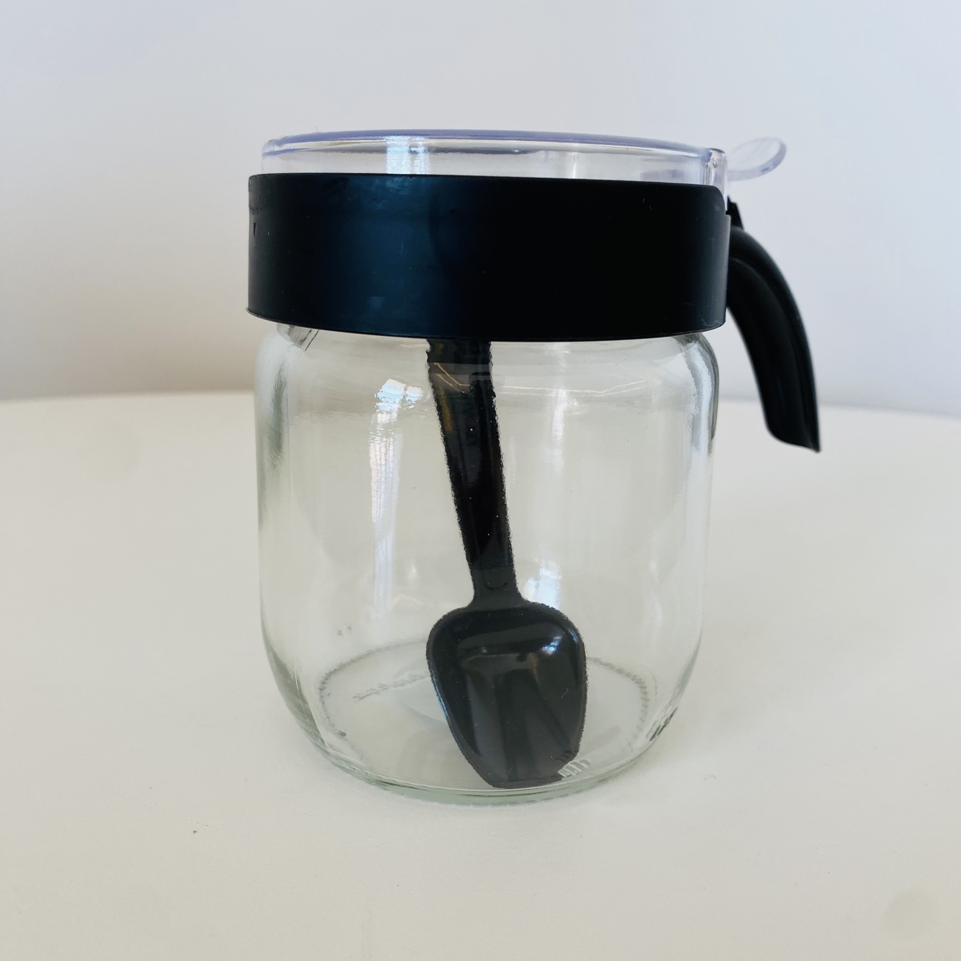 Frasco de vidro com tampa preta e colher no interior