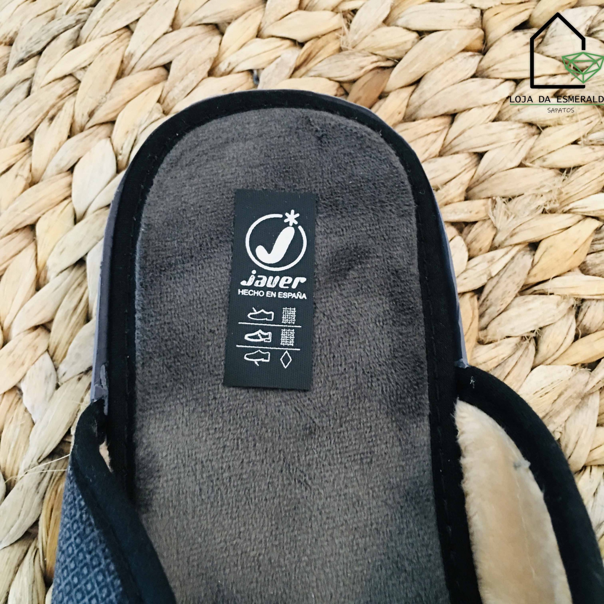 Pantufa cinzenta com interior de pelo bege e etiqueta 'javer HECHO EN ESPAÑA' em superfície de fibras naturais