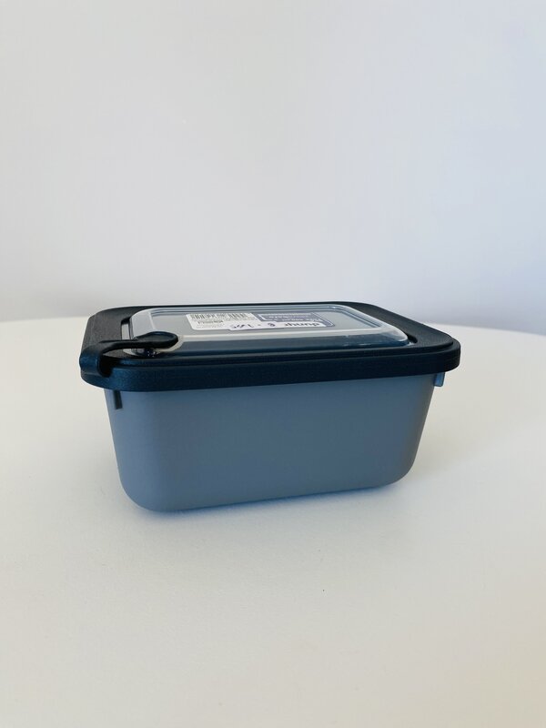 Caixa de plástico rectangular gris com tampa preta e etiqueta