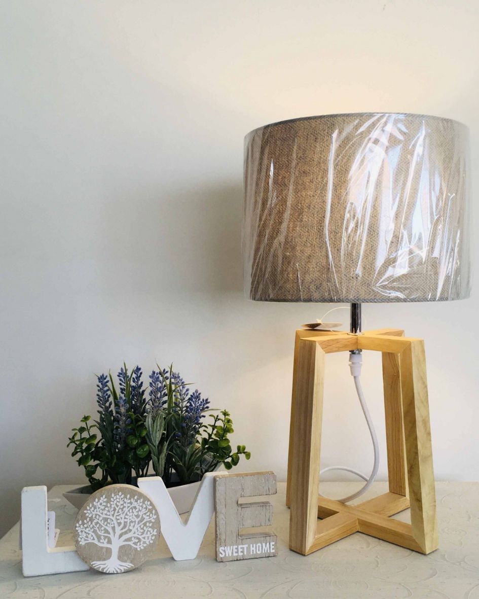 Abajur de madeira e tecido com decoração LOVE e plantas artificiais numa mesa branca