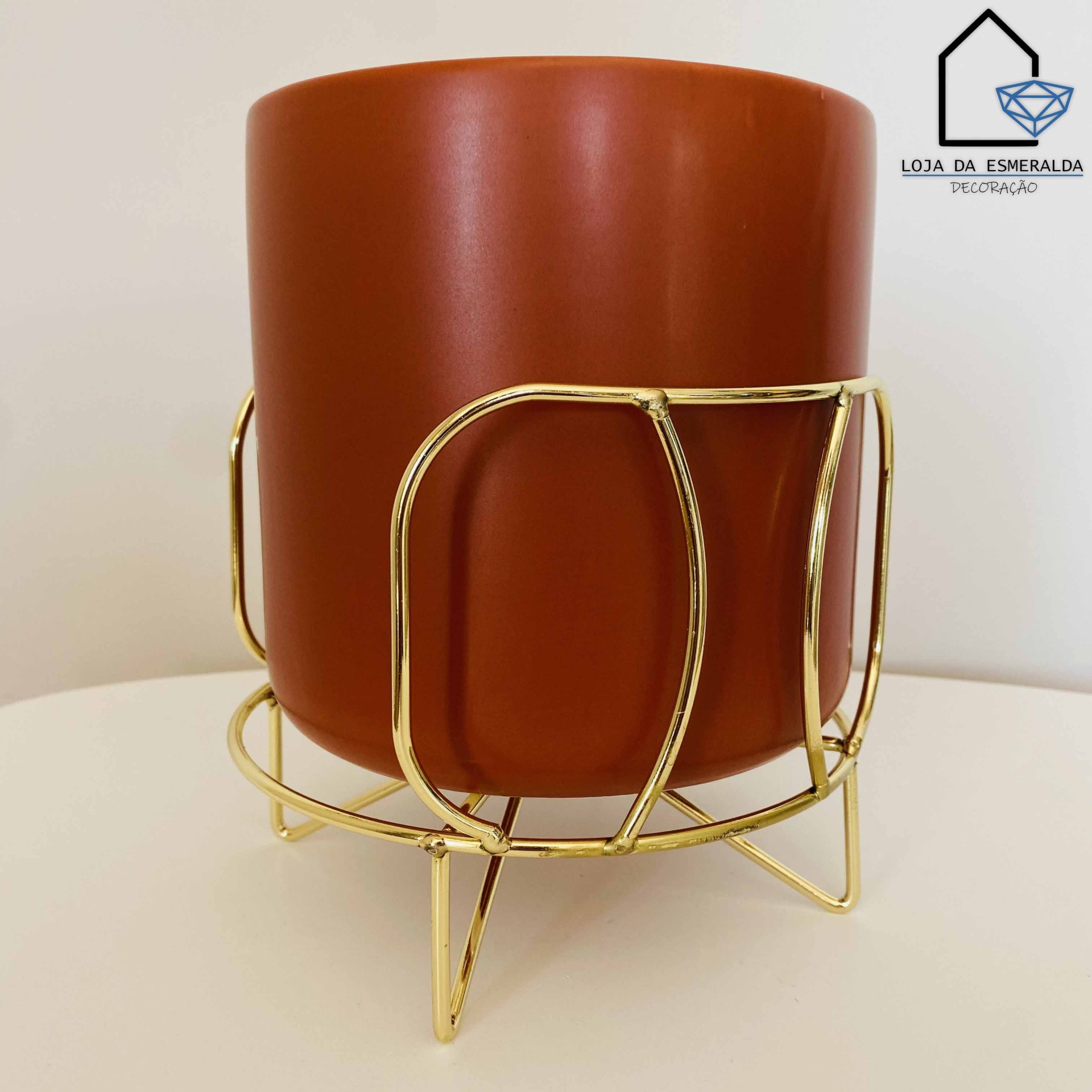 vaso castanho em suporte metálico dourado num fundo claro