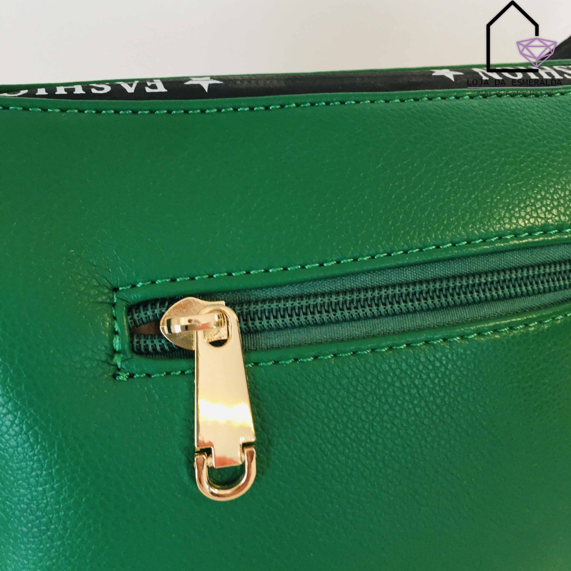 Mala verde com zíper dourado e parte superior preta com desenhos brancos