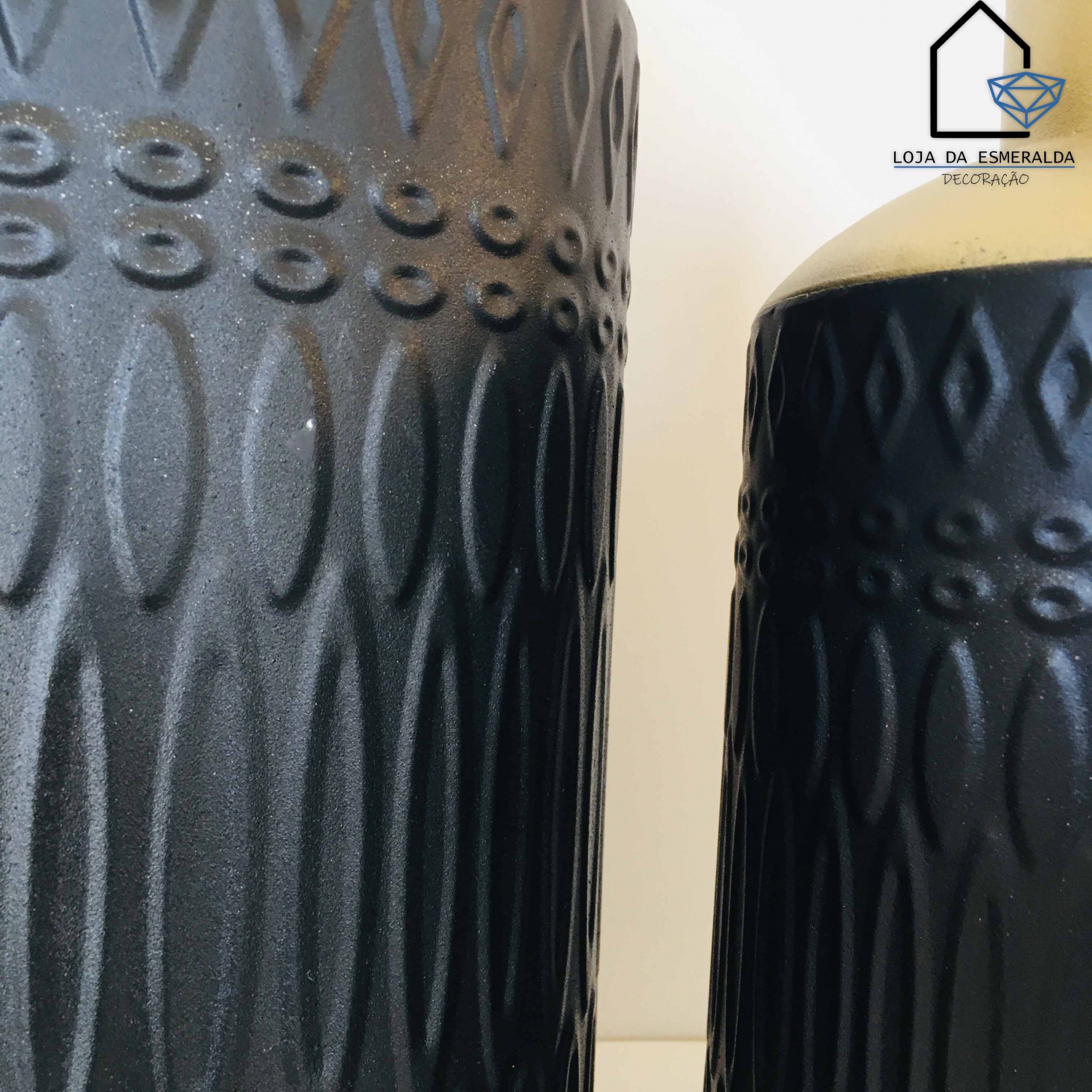 Dois vasos pretos com padrões em relevo e logótipo de loja no canto superior direito