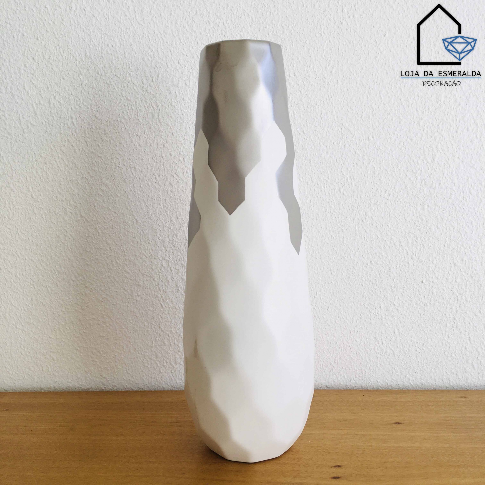 Vaso de cerâmica branco e cinzento com textura facetada sobre mesa de madeira