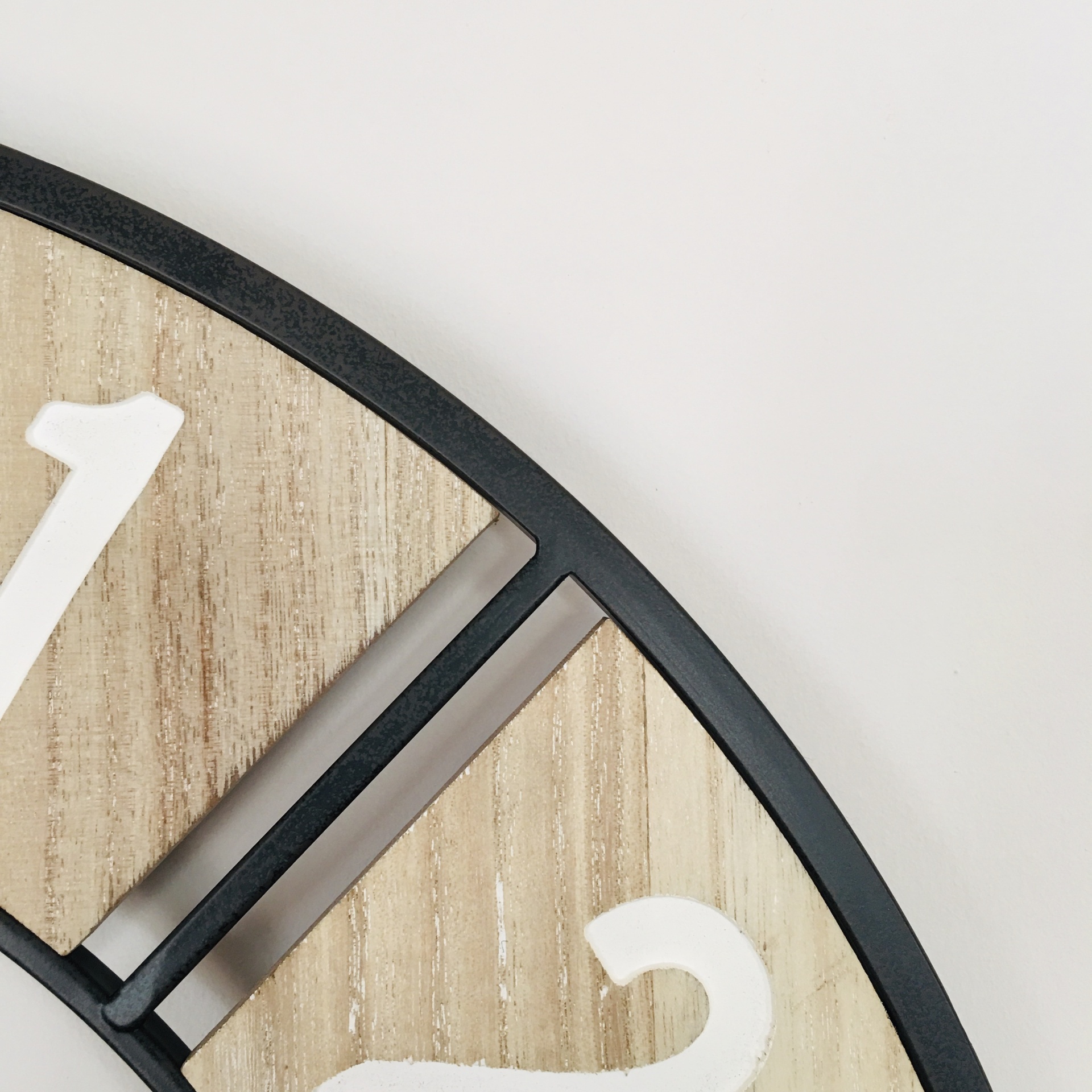 Relógio de parede com números brancos, estrutura preta e fundo de madeira.